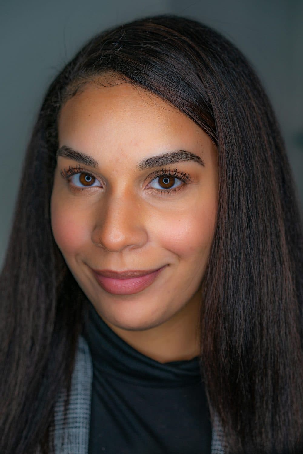 A young woman with long dark hair photographed close up, looking straight at the camera