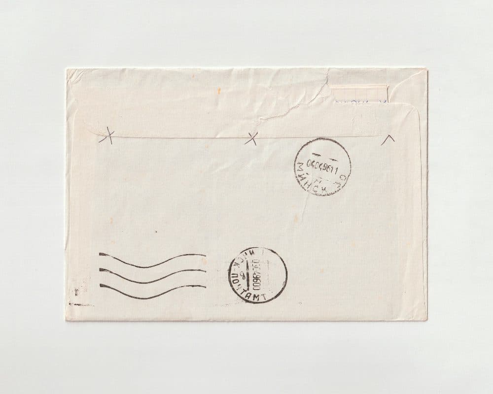 The back of an old cream paper envelope with two round black postmarks and three wavy cancellation lines stamped in ink
