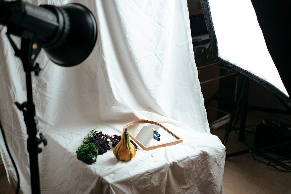 A product photo setup with studio lights, a white backdrop and small items