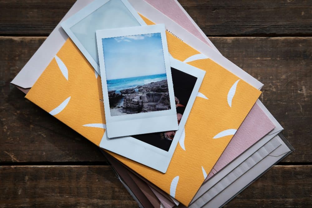 Upright instant photo prints of a seaside view lying on patterned envelopes