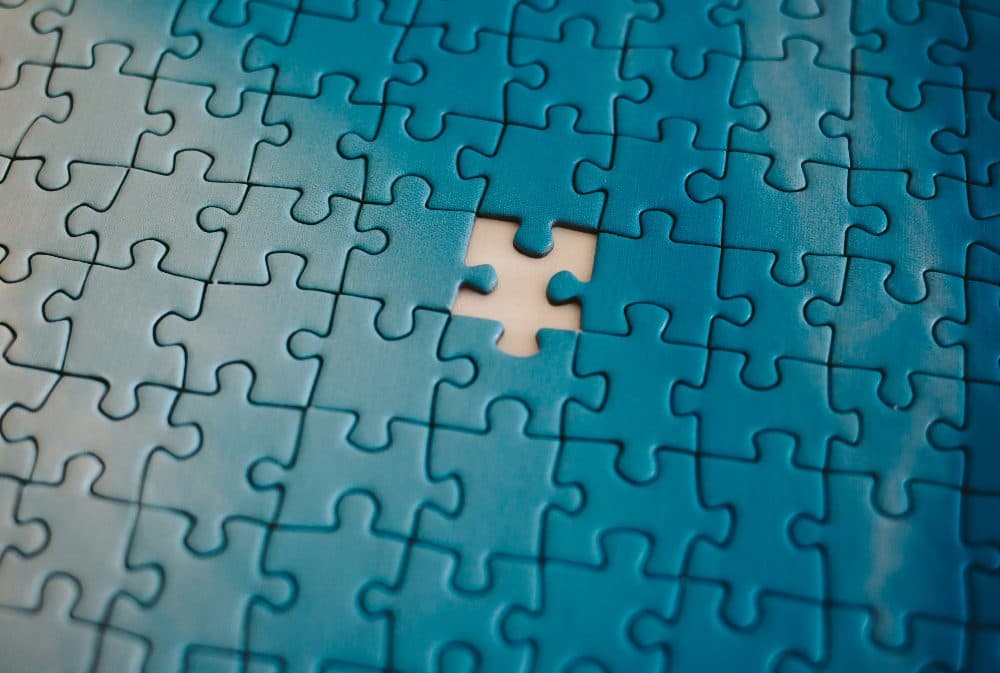 A teal jigsaw puzzle with one piece missing from the middle