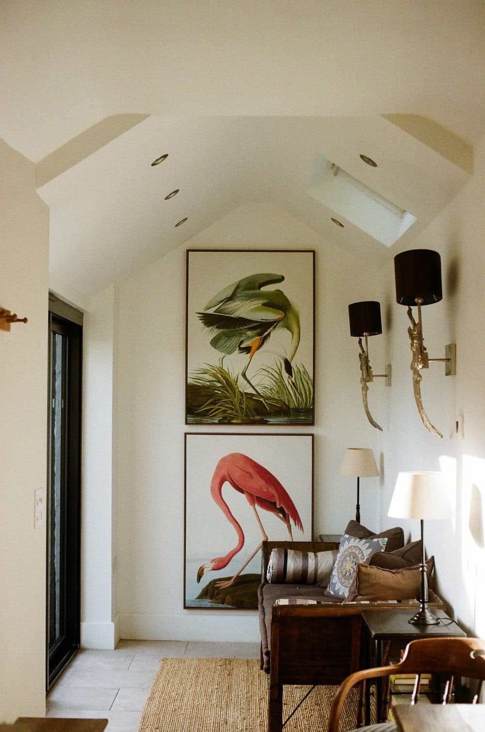 Two large framed bird prints, a heron above a flamingo, hanging on a white wall above a sofa