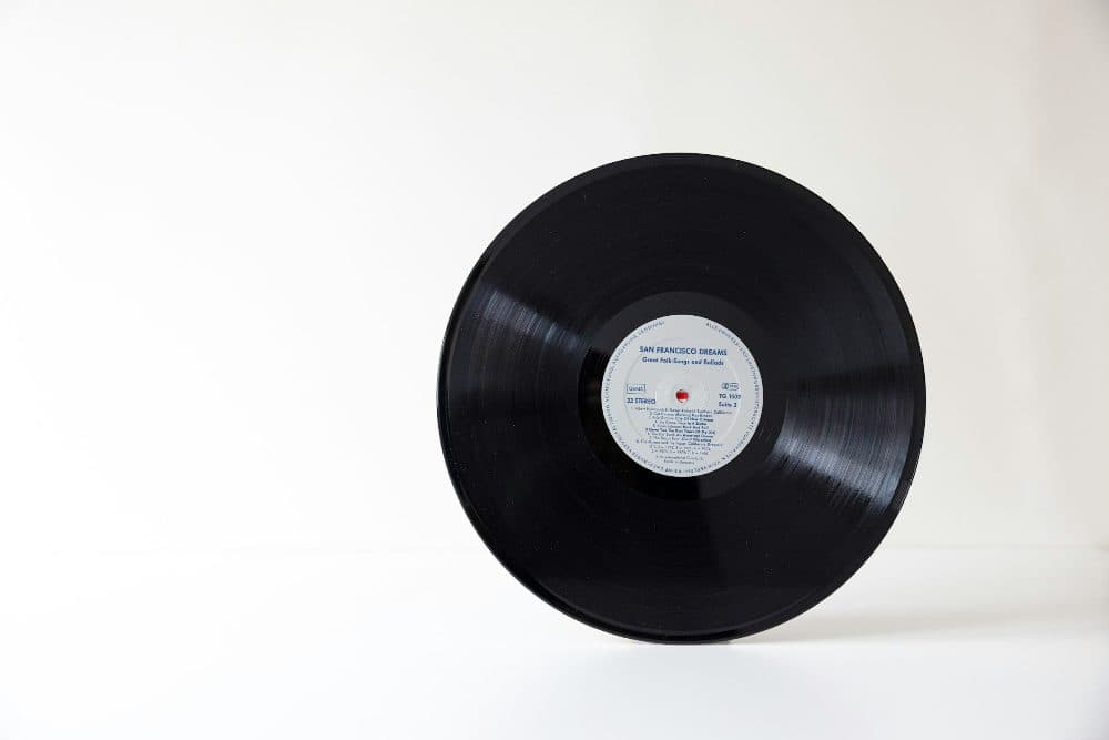 A black vinyl record standing upright on a plain white surface