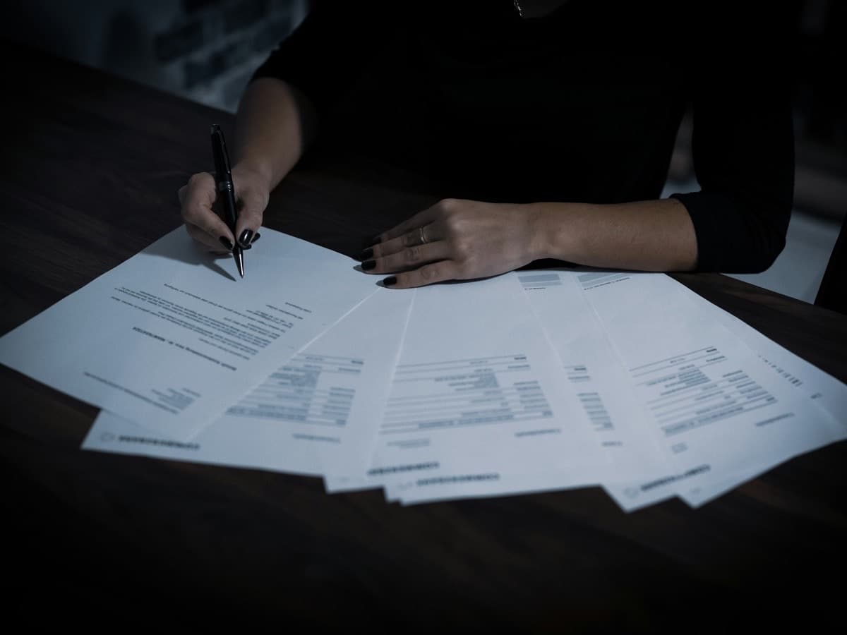 A woman at a table working through a spread of printed application papers