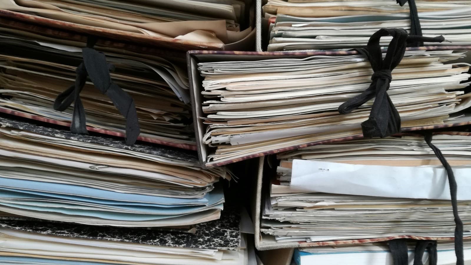 A row of thick brown ring binders standing on a shelf