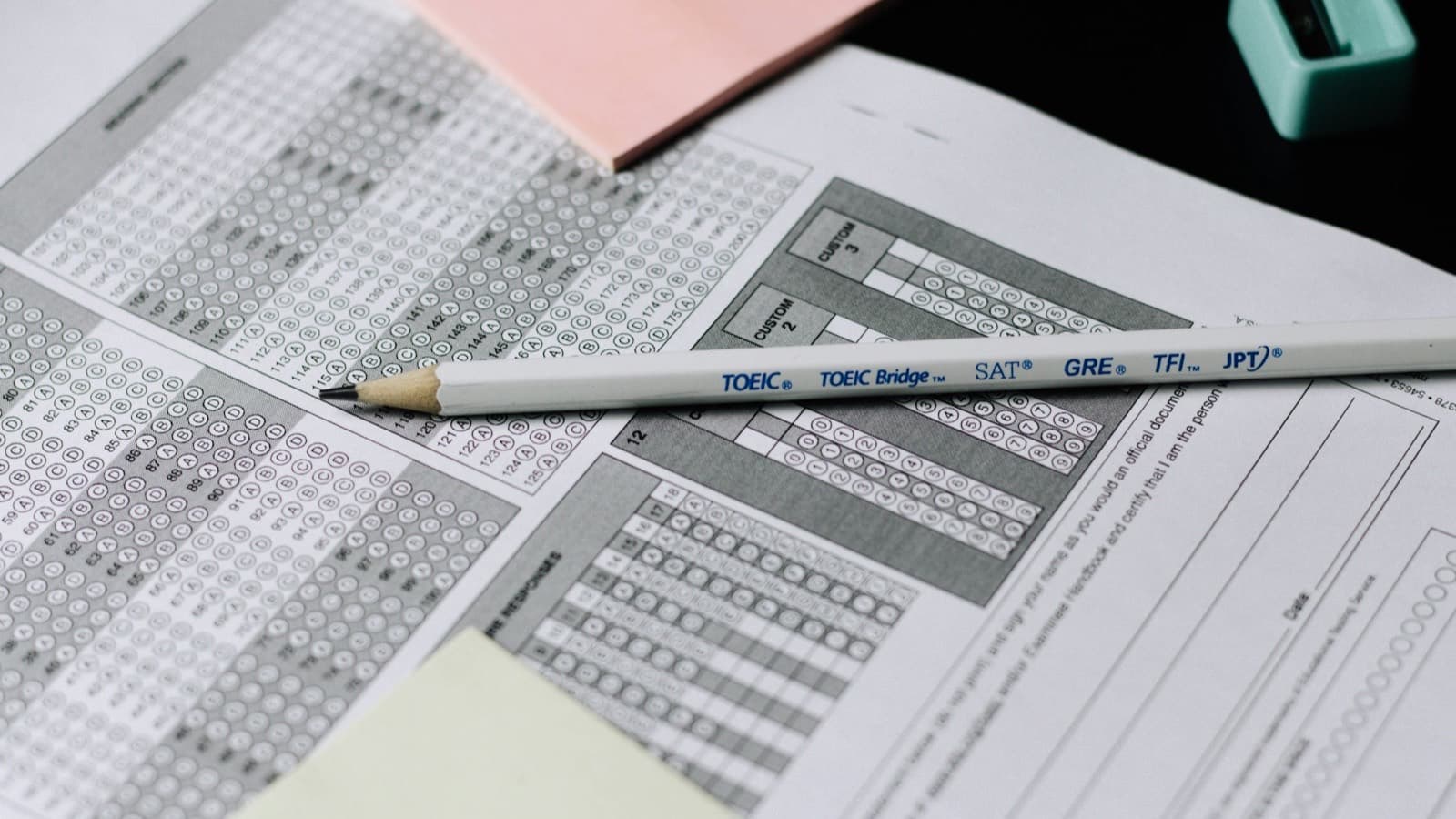 A pencil resting on a multiple-choice answer sheet with a pink sticky note