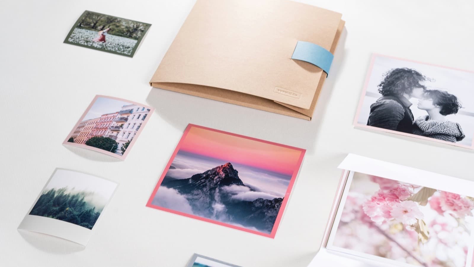 Printed photographs and books spread on a white table