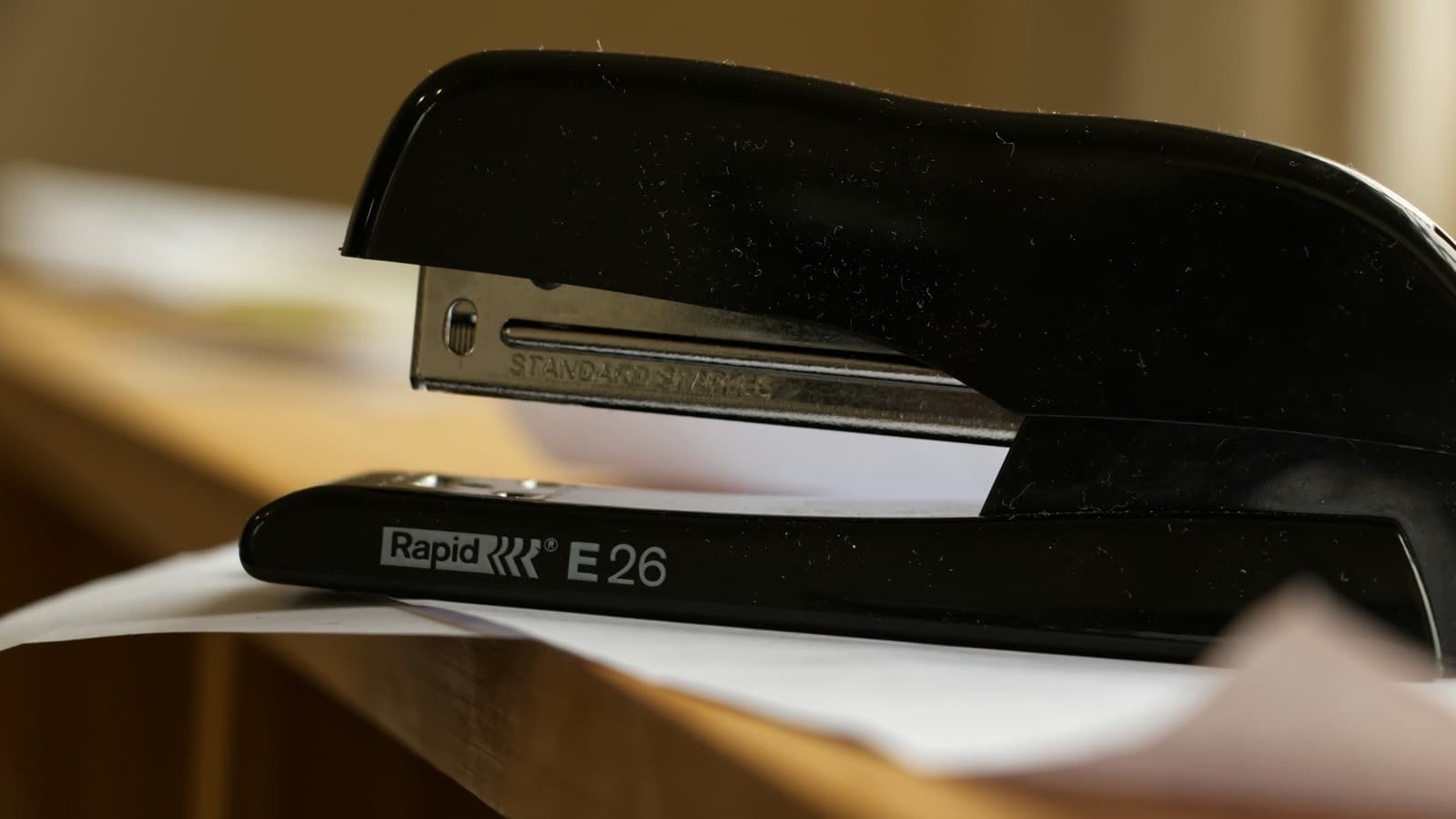 A black stapler on a desk beside a set of printed documents