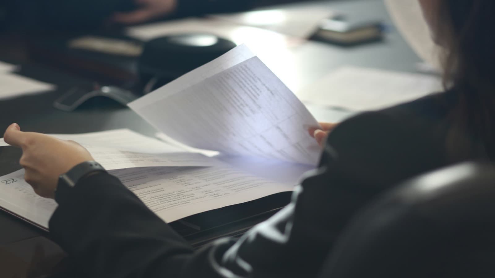 A woman sitting at a table reading through printed pages