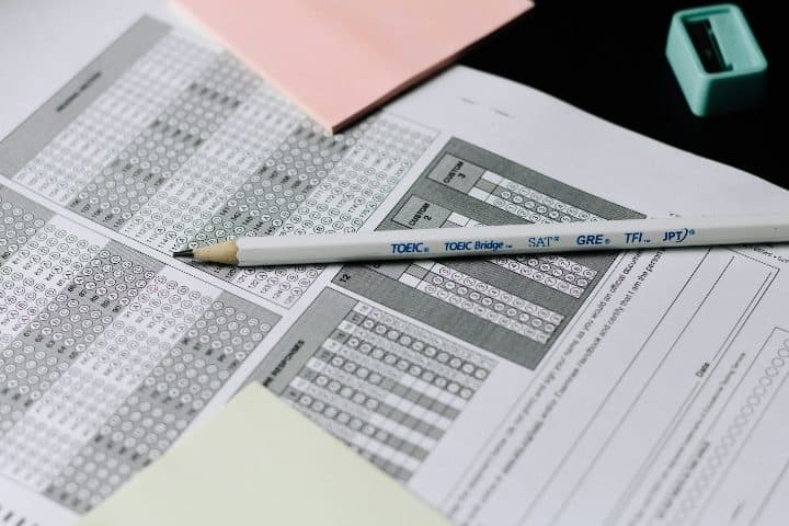 A pencil resting on a multiple-choice answer sheet with a pink sticky note