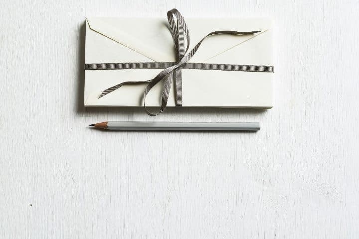 A white envelope and a grey pencil on a white surface